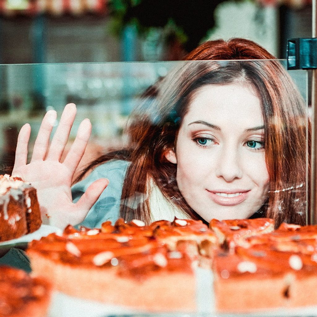 Eine Frau schaut durch eine Vitrine auf einen Kuchen