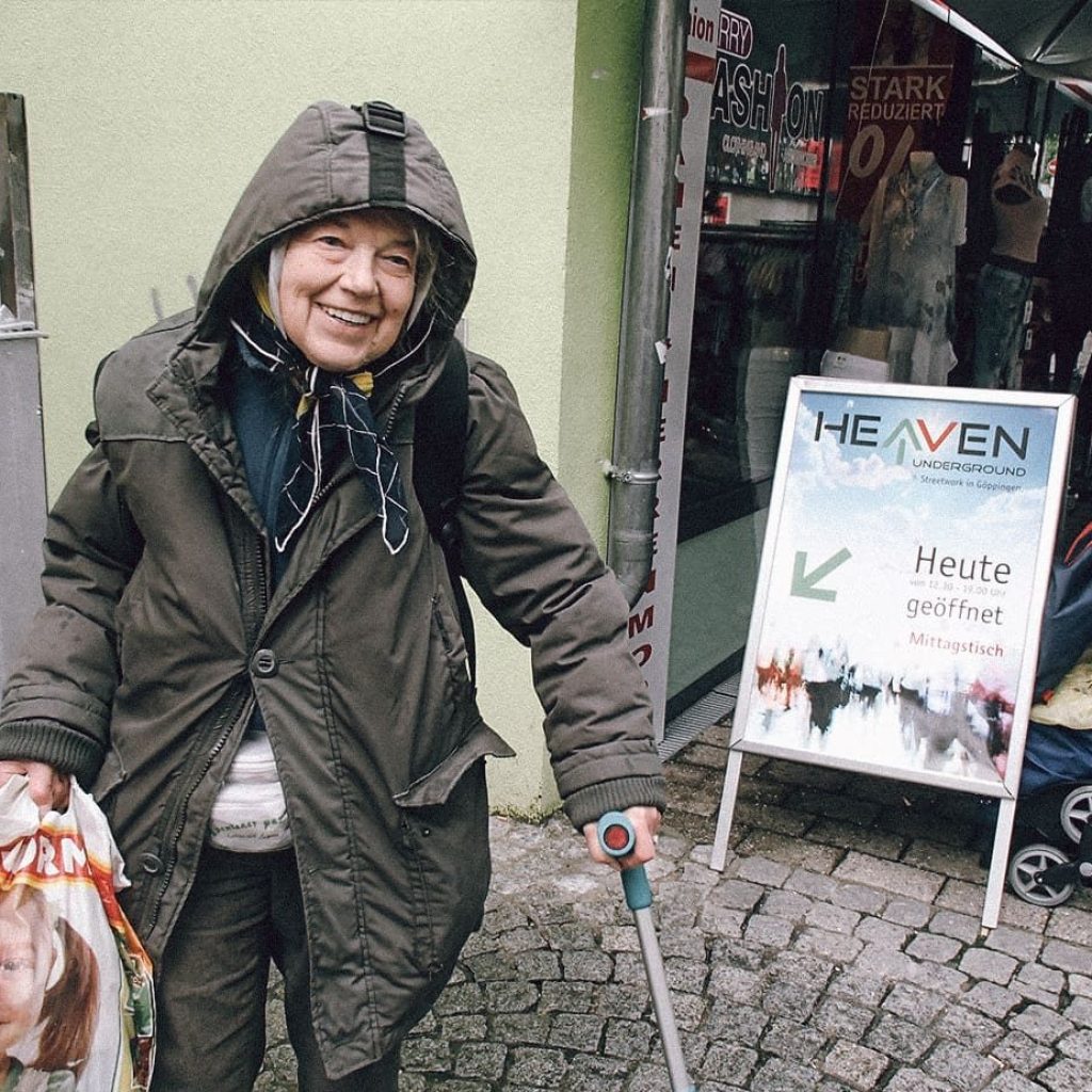 Eine ältere Dame mit Gehstock und einer Einkaufstüte vor dem Eingang des Heaven Underground