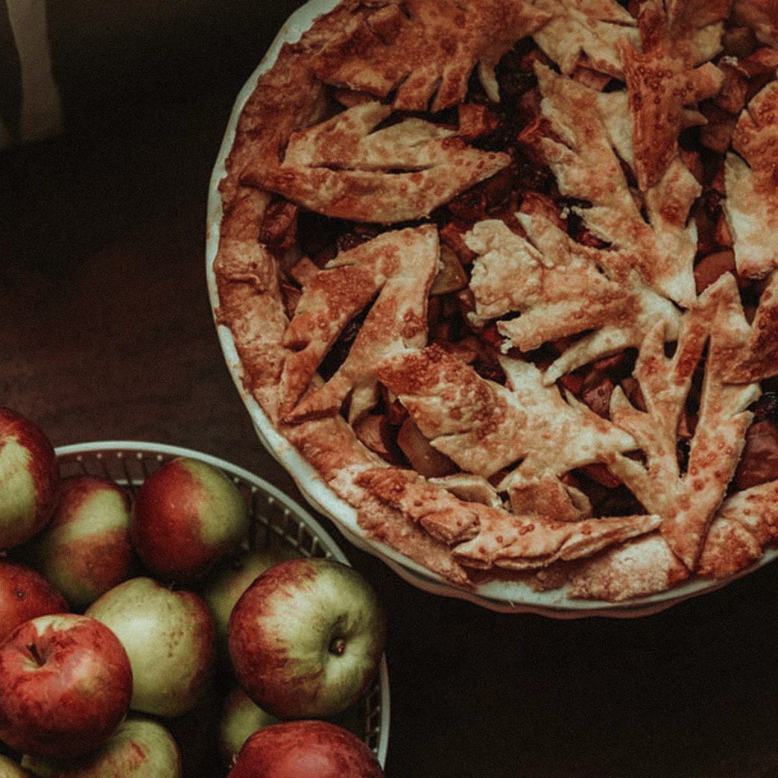 Selbstgemachter Ofenschlupfer sowie eine Schüssel voller Äpfel stehen auf einem Tisch