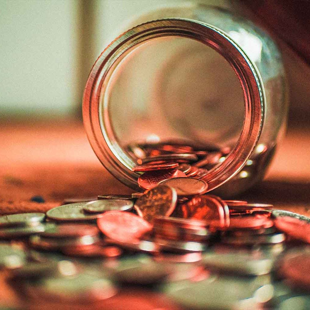 Münzen aus einem Glas symbolisieren Finanzen