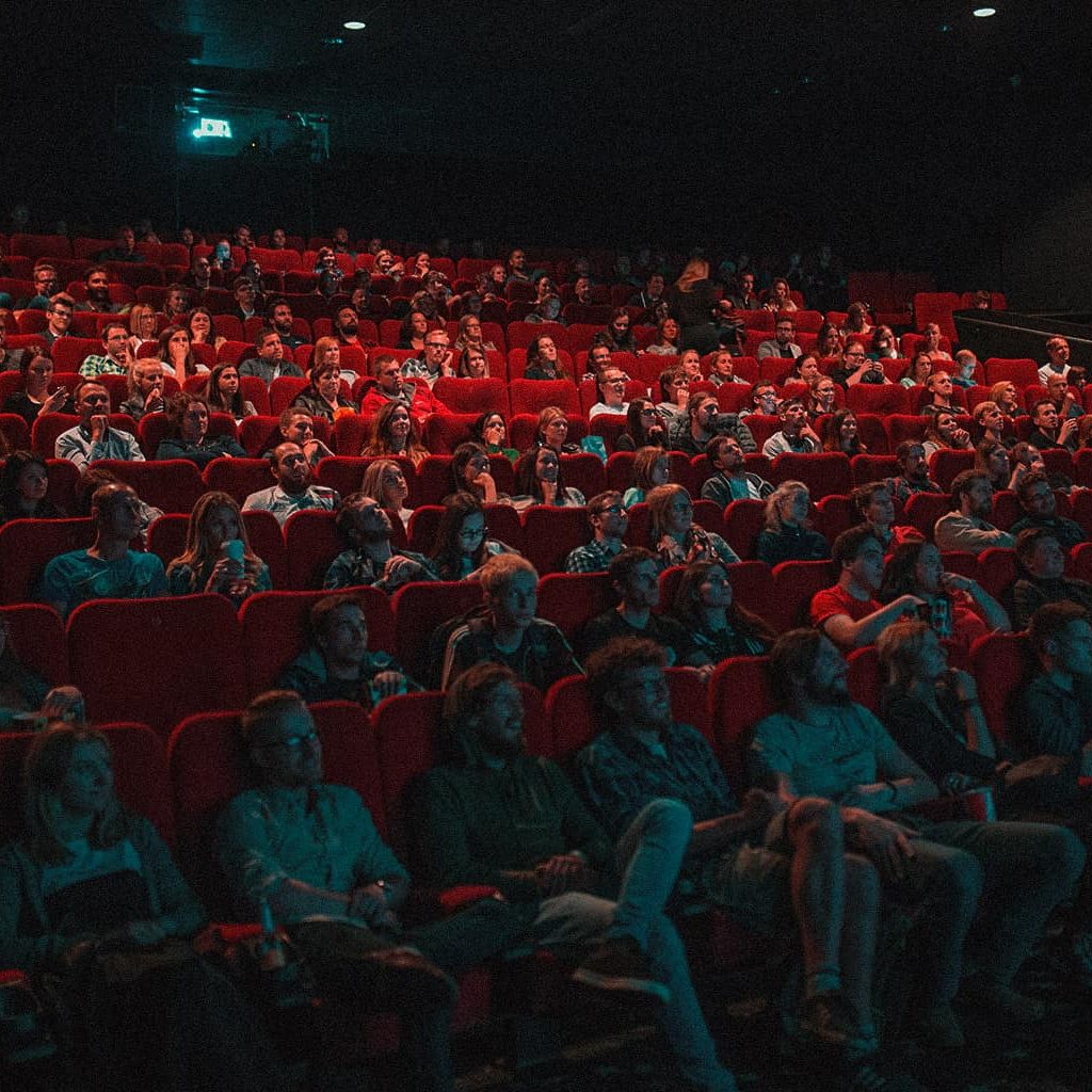 Viele Menschen sitzen in einem Kinosaal und schauen gespannt auf die Leinwand
