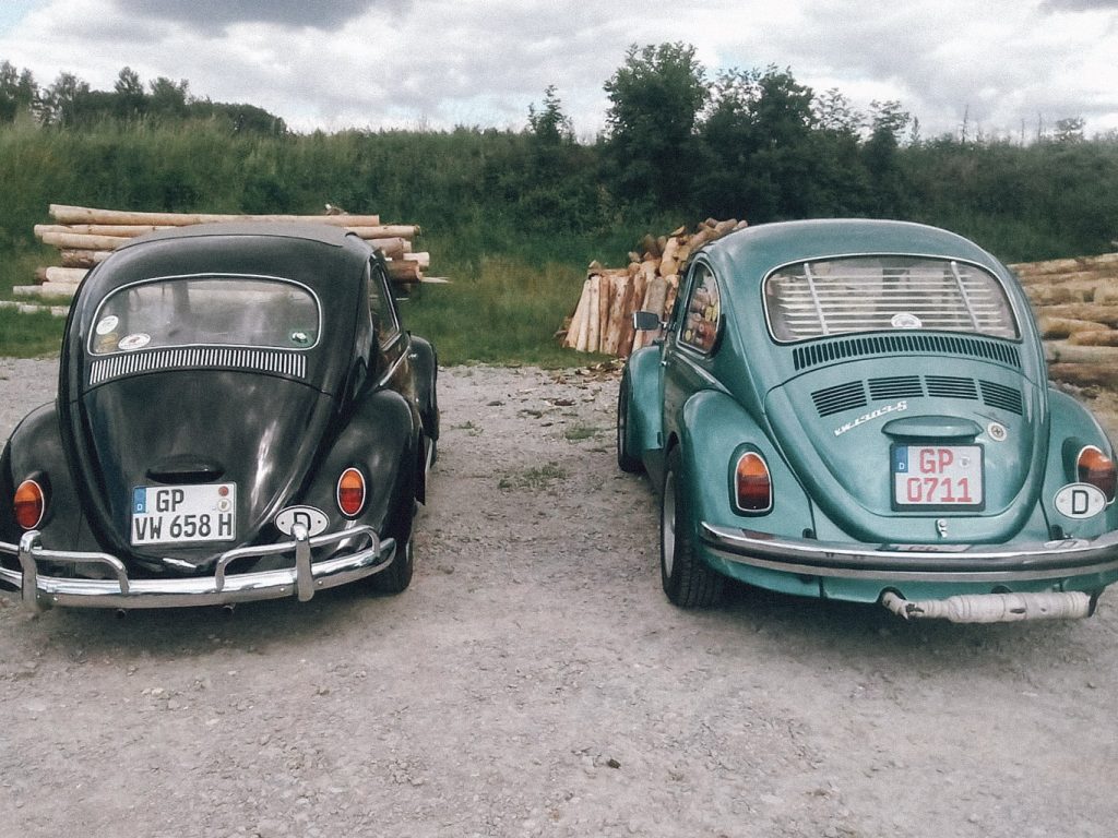 Zwei geparkte VW Käfer auf einem Schotterplatz