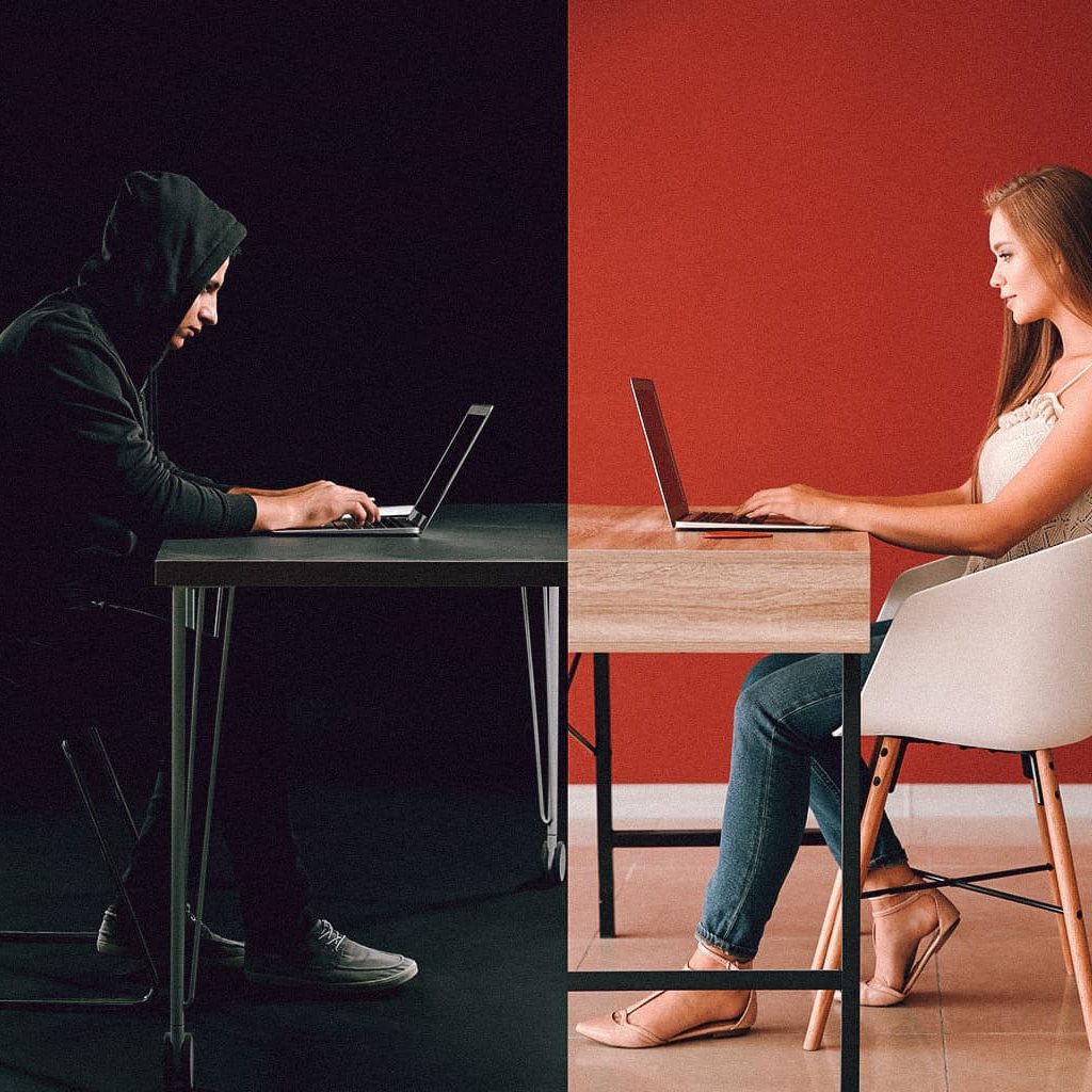 Ein Mann mit Kaputzenpulli vor einem schwarzen Hintergrund sitzt einer Frau in einem hellen Raum gegenüber