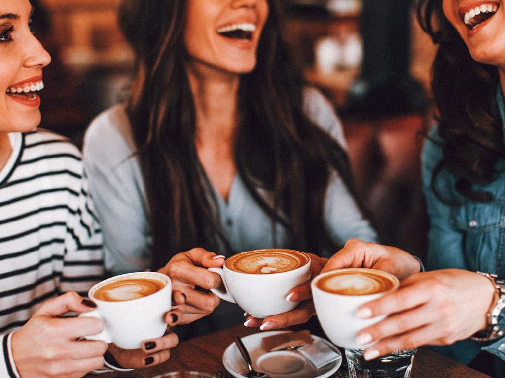 Drei Frauen lachen und trinken einen Kaffee