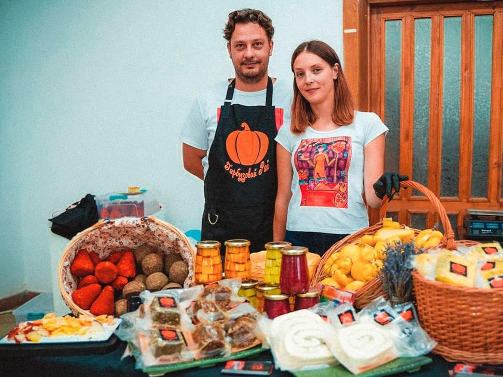 Eine Frau und ein Mann stehen hinter einem Tisch, auf dem verschiedenes Gemüse dargeboten wird