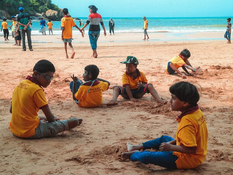 Kinder mit T-Shirts der FRIENDS Kinderhilfe International Sri Lanka sitzen am Strand