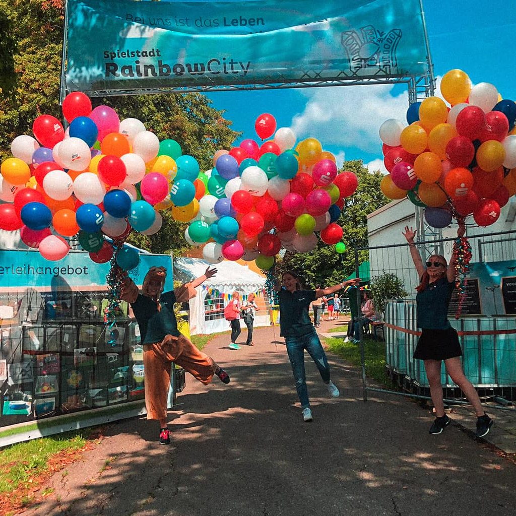 Der Eingang der Spielestadt Rainbow-City mit vielen bunten Luftballons