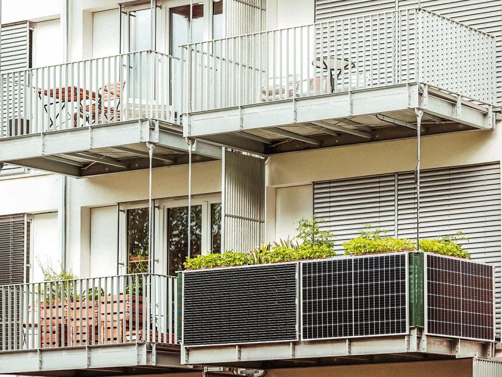 Ein Balkonkraftwerk steht auf dem Geländer eines Balkons in einem modernen Neubau.