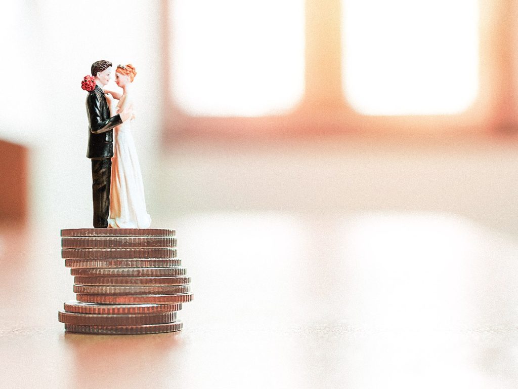 Ein Keramik-Brautpaar steht auf einem Stapel von Münzen