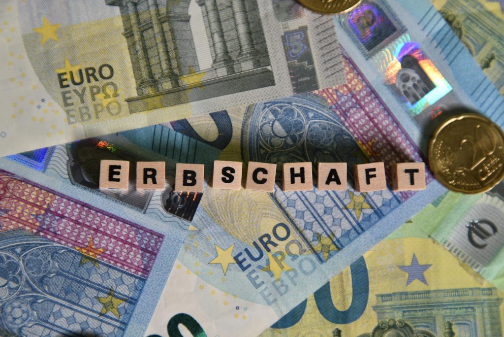 Auf einem Haufen von Euro-Banknoten steht das Wort Erbschaft