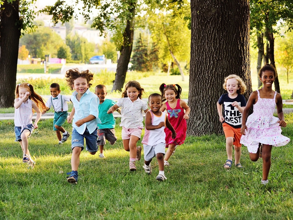 Eine Gruppe diverser Kinder läuft lachend durch einen sonnigen Park – im Rahmen der WirWunder Verdopplungsaktion Weltkindertag 2025.