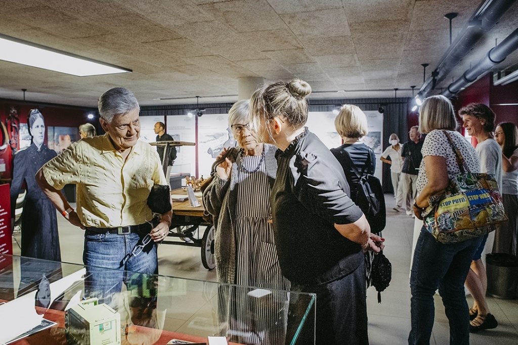Besuchergruppe bei einer Führung im Friederike-Wackler-Museum, im Gespräch vor einer historischen Vitrine.