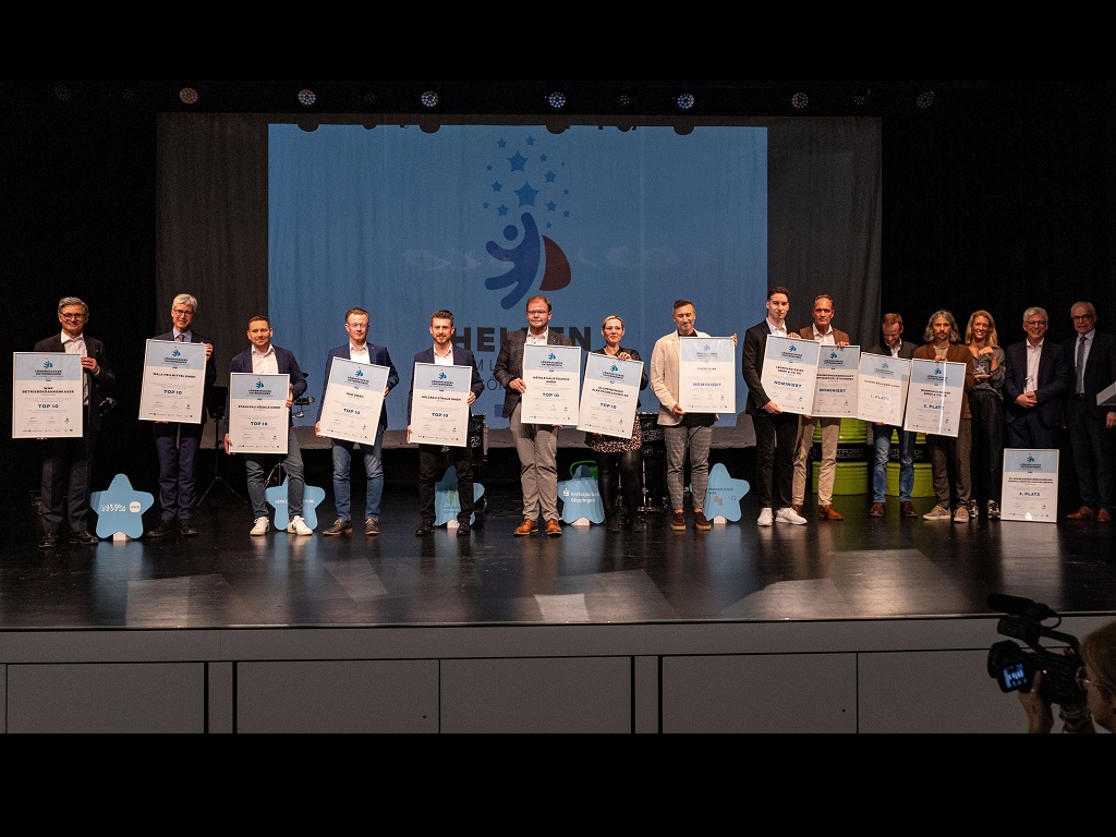Teilnehmende Unternehmen der Heldenwahl 2023 auf der Bühne – ausgezeichnet für besonderes Engagement mit Urkunden und Plaketten.