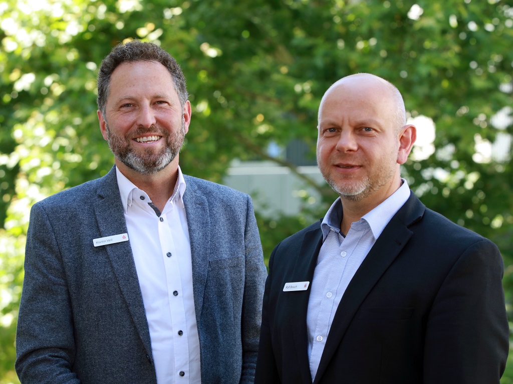 Referenten auf der Messe für Generationen: Martin Veil und Ralf Bosch, zwei Mitarbeiter der Kreissparkasse Göppingen, stehen im Freien nebeneinander und lächeln in die Kamera, beide im Anzug mit Namensschild.