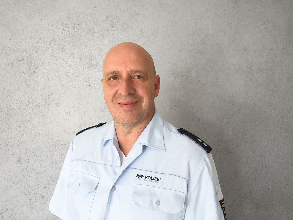 Referent auf der Messe für Generationen: Ralf Liebrecht, Polizeibeamter in Uniform vor grauem Hintergrund, lächelt in die Kamera.