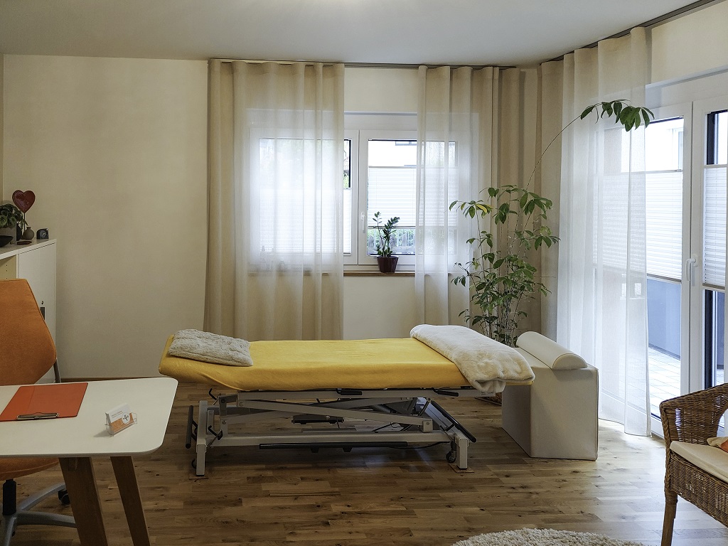 Lichtdurchfluteter Behandlungsraum mit gelber Therapieliege in der osteopathischen Praxis von Bettina Vollmer in Bad Boll.