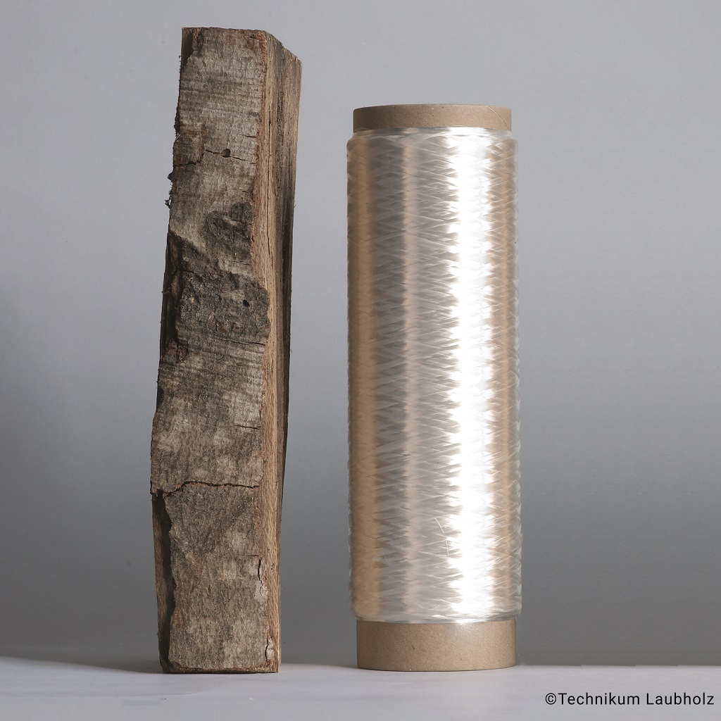 Von Holz zu Hightech: Rohes Buchenholz neben fertiger Spule aus nachhaltiger Holzfaser.