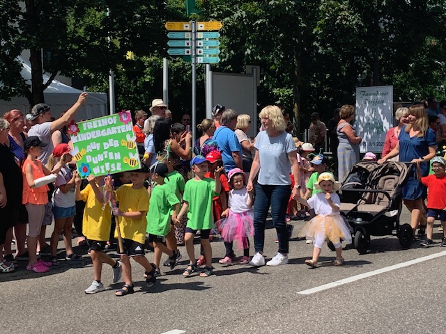 Kinder des Freihof-Kindergartens in bunten T-Shirts und Kostümen beim Festumzug 2023 in Faurndau – mit kreativem Schild und viel guter Laune.