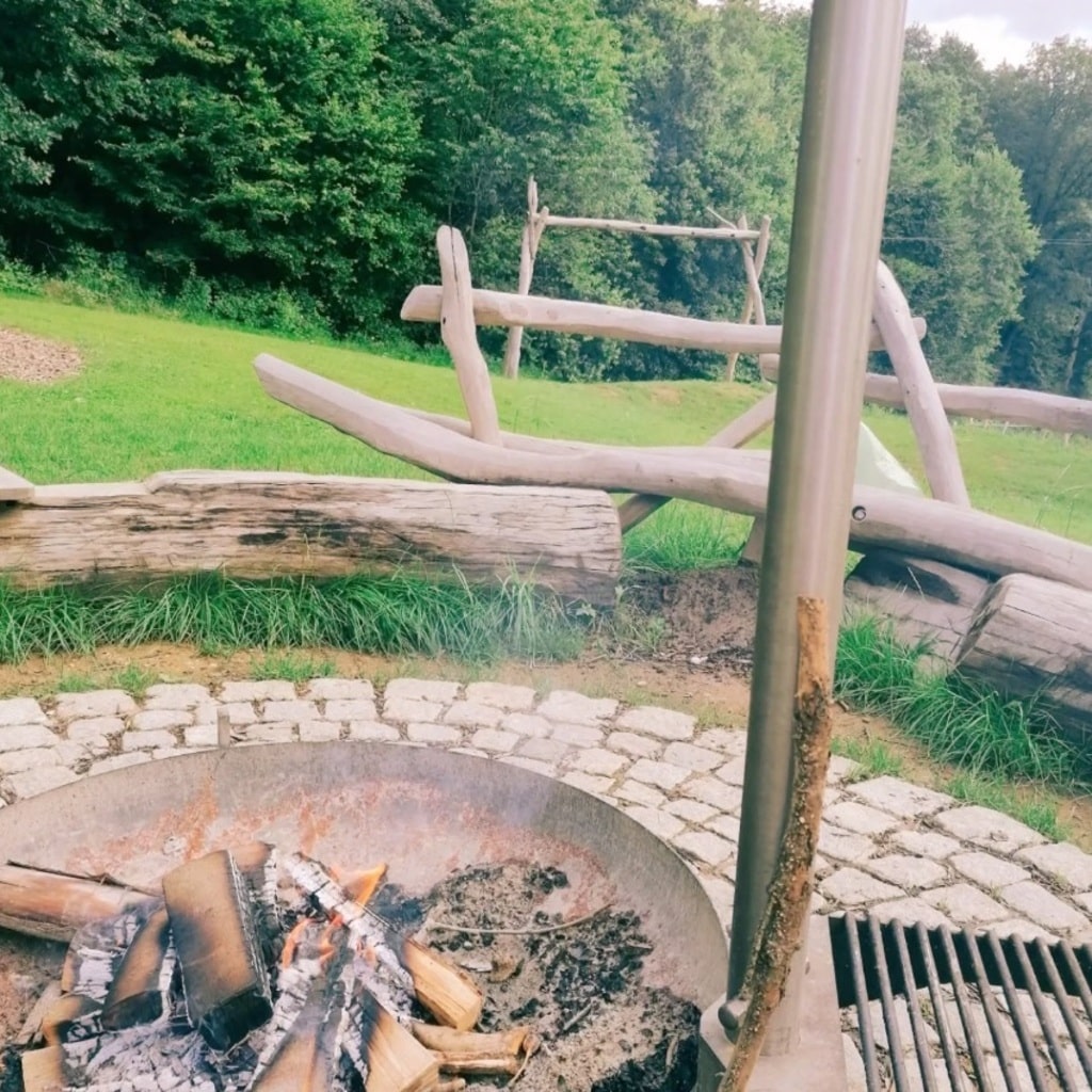 Grillstelle mit Feuerstelle und Holzsitzbank in naturnaher Umgebung des Waldspielplatzes in Wäschenbeuren.