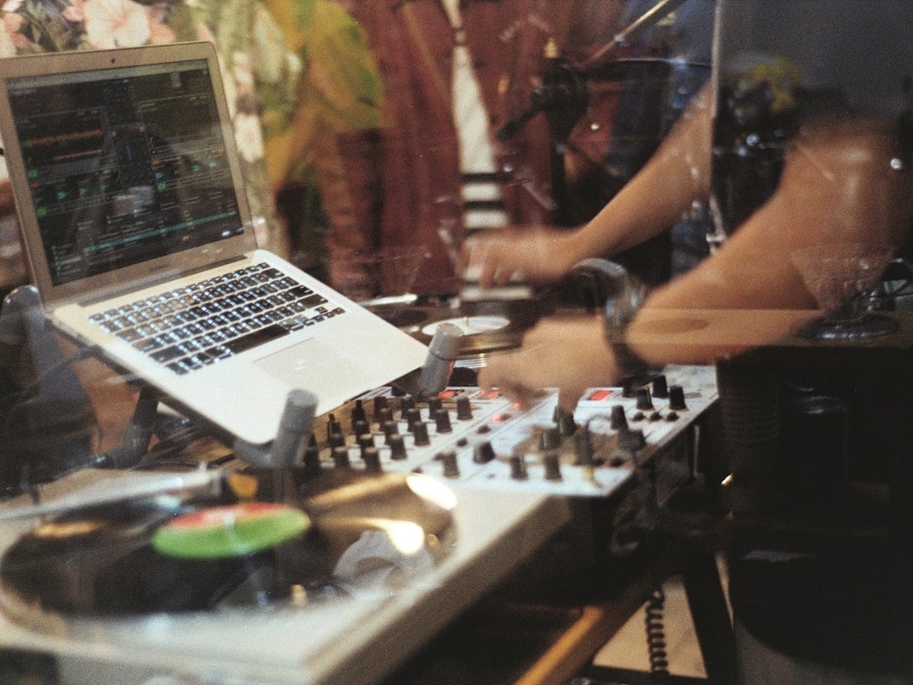 DJ-Equipment mit Plattenspieler, Mischpult und Laptop in einem Tonstudio, während eine Person an den Reglern arbeitet – ein Einblick in die Welt der Musikproduktion im Rahmen des Schülerferienprogramm Süßen 2025.