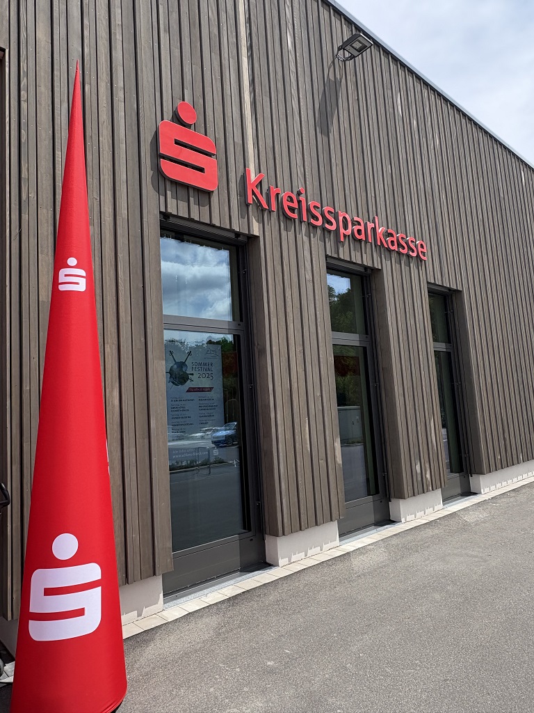 Außenansicht der neuen Kreissparkassen-Filiale in Wäschenbeuren mit moderner Holzfassade, großen Fenstern und rotem Sparkassen-Logo über dem Eingang.