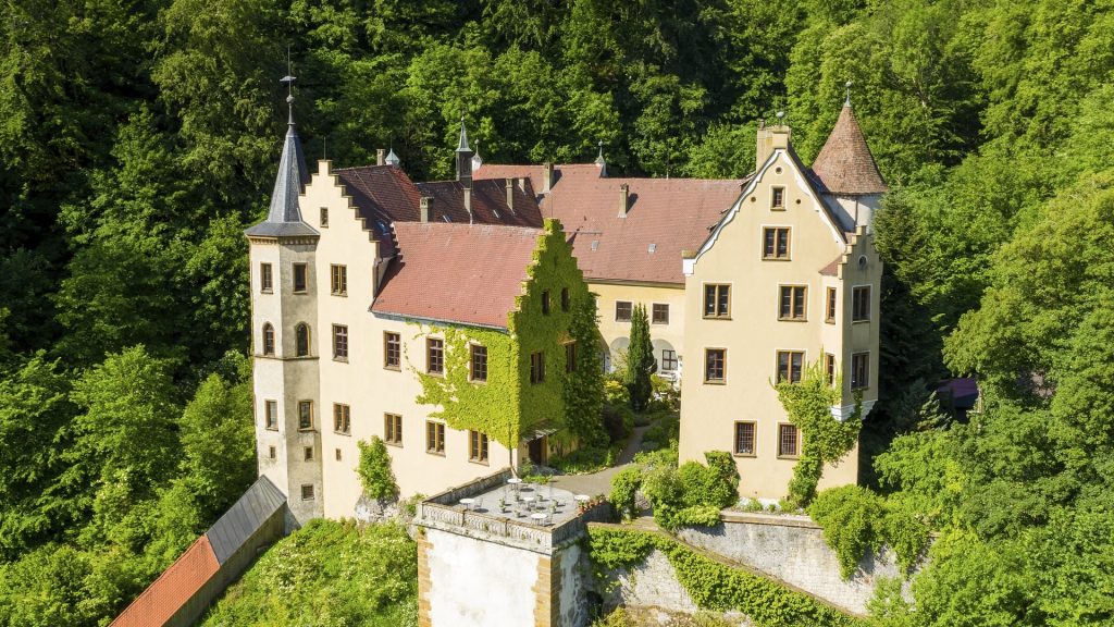 Majestätisches Schloss Weißenstein umgeben von dichtem Sommergrün – ein einladender Ort für Entdeckungen, Familienausflüge und märchenhafte Erlebnisse.