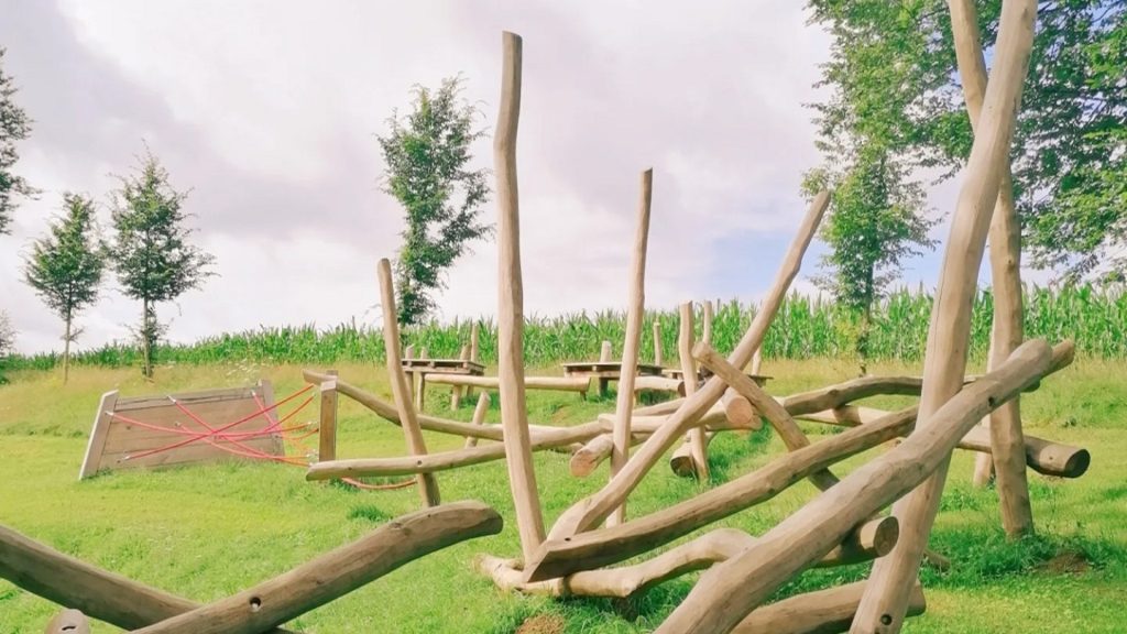 Holz-Klettergerüst auf Wiese mit Blick auf Felder und Bäume – Waldspielplatz in Wäschenbeuren.