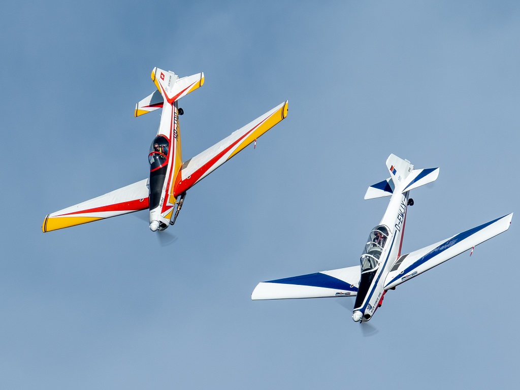 Zwei doppelsitzige Zlin Z-526 Trener Master des Dragon Trener Teams fliegen bei den Donzdorfer Flugtagen 2025 synchron in enger Formation am Himmel – elegant lackiert in Blau-Weiß und Rot-Gelb.
