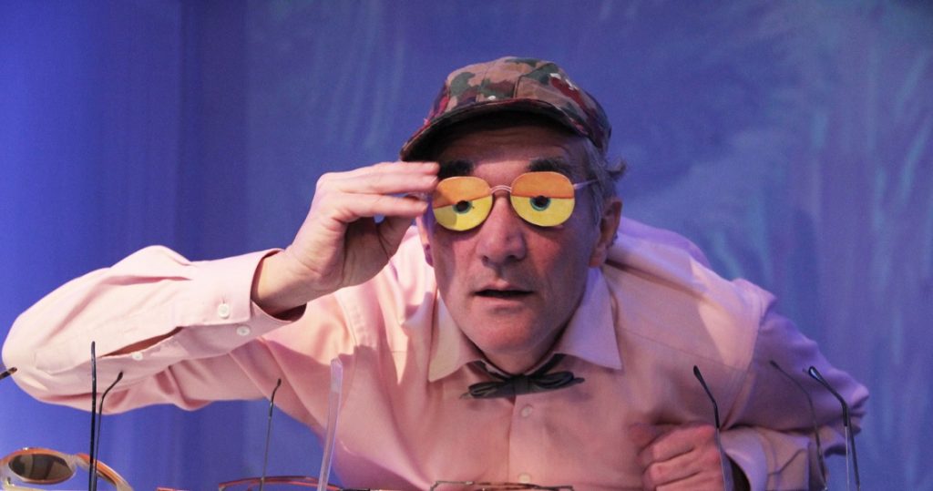 Schauspieler mit gelber Brille und Tarnkappe auf der Bühne – Szene aus der schwäbischen Satire „Die sieben Schwaben“ im Nachmittagstheater Süßen.