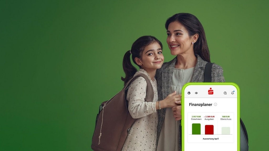 Mutter und Tochter lächeln, daneben Smartphone mit Finanzplaner zur Übersicht von Einnahmen und Ausgaben.