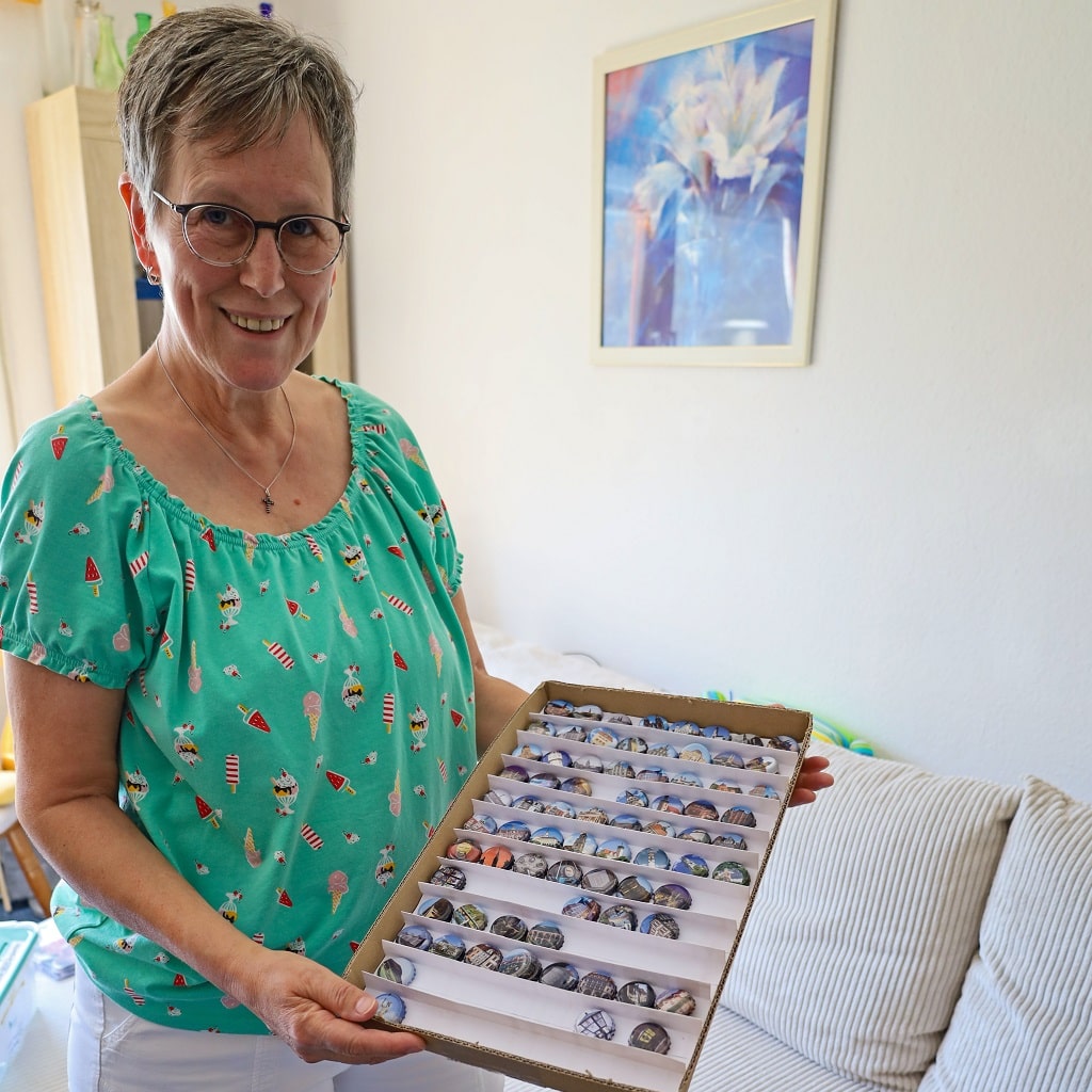 Ingeborg Lindauer zeigt besondere Kronkorken in einem Setzkasten