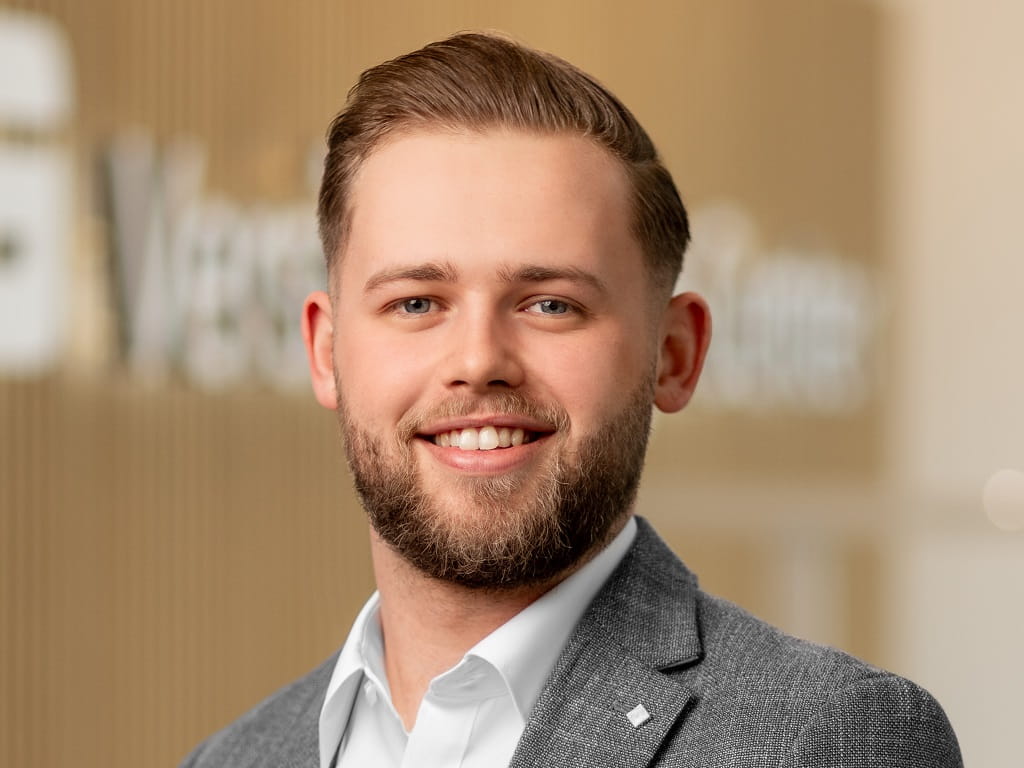 Porträt von Leon Boyes, Fachberater im S-Versicherungs-Center Göppingen, in grauem Sakko und weißem Hemd, freundlich lächelnd vor neutralem Hintergrund.