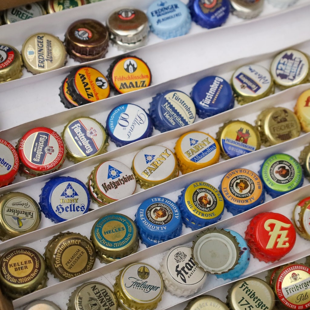 Nach Marken sortierte Kronkorken im Setzkasten, z. B. Fürstenberg oder Erdinger