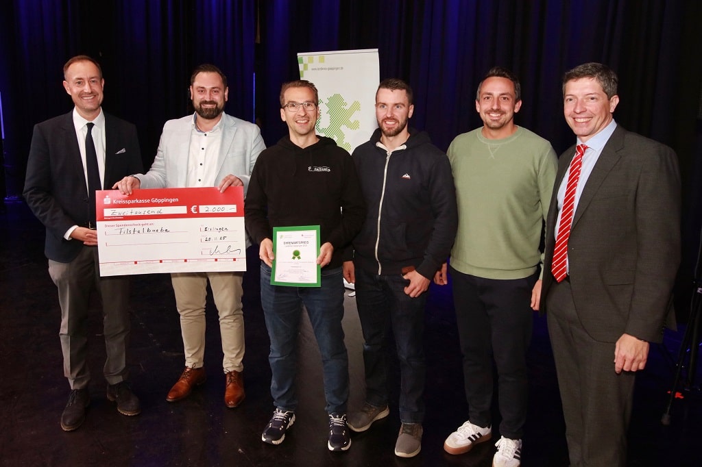 Die Gewinner des ersten Preises beim Ehrenamtspreis Landkreis Göppingen 2025 stehen gemeinsam auf der Bühne. Ein Mitglied der Filstalbuaba hält die Urkunde, daneben wird der symbolische Spendenscheck über 2.000 Euro präsentiert. Links und rechts stehen Vertreter des Landkreises und der Kreissparkasse.