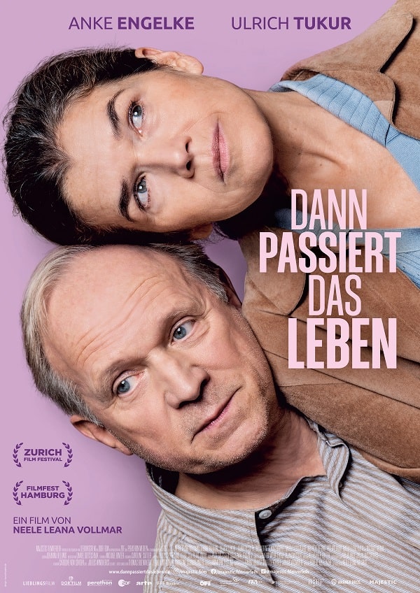 Filmplakat zu „Dann passiert das Leben“ beim Kino Klub K3 mit Anke Engelke und Ulrich Tukur, beide eng nebeneinander vor rosafarbenem Hintergrund, nachdenkliche Blicke, Filmtitel gut sichtbar platziert.