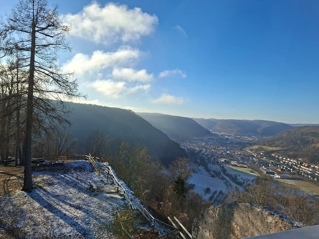 Aussicht über das Tal bei Bad Ditzenbach mit Blick auf den Ort, umliegende Hügel und die winterliche Landschaft unter blauem Himmel.