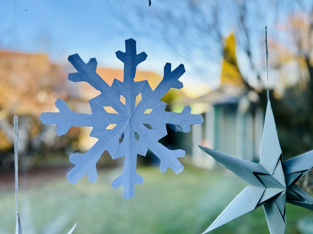 Papier-Schneeflocke als Winterdekoration am Fenster.