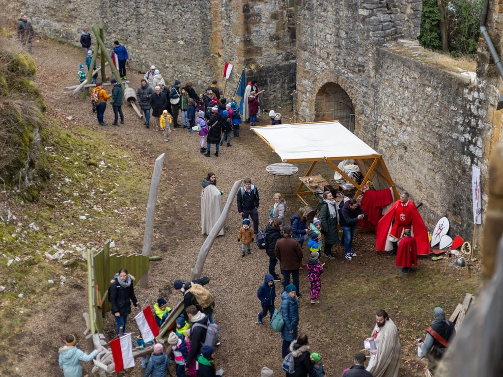 Besucherinnen und Besucher bummeln zwischen Marktständen und historischen Mauern.
