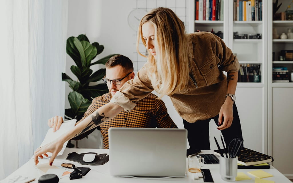 Frau und Mann sortieren Bescheinigungen und Unterlagen am Schreibtisch.