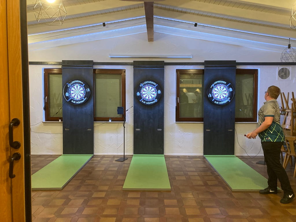 Dartspieler der beim Training an mehreren Dartscheiben im Vereinsheim
