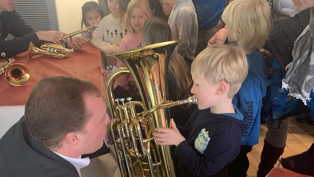 Kind probiert bei der Instrumenteninformation der Jugendmusikschule Göppingen ein Blechblasinstrument unter Anleitung eines Lehrers aus.