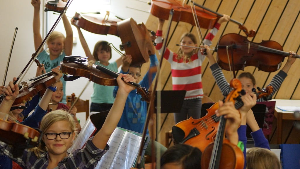 Kinder präsentieren bei der Instrumenteninformation der Jugendmusikschule Göppingen ihre Streichinstrumente im Unterrichtsraum.