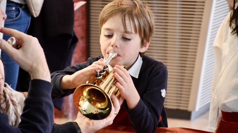 Ein Junge testet konzentriert eine Trompete bei der Instrumenteninformation der Jugendmusikschule.