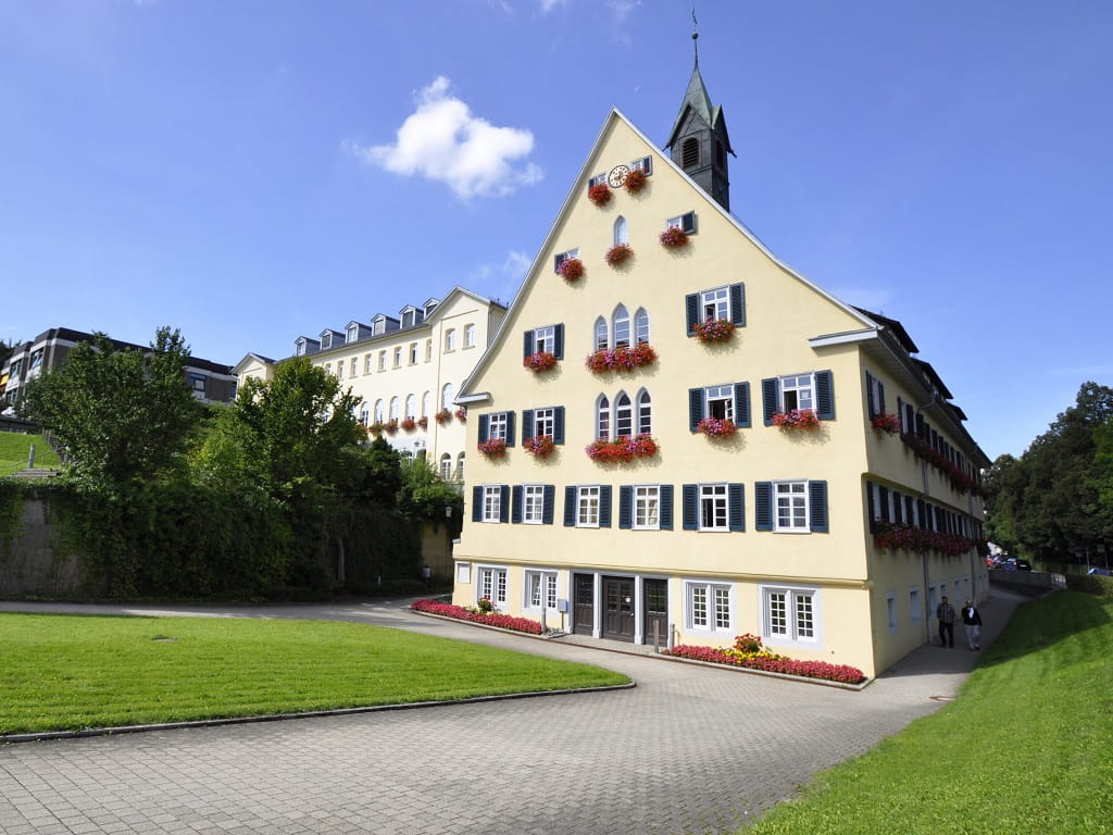 Außenansicht des MuSeele im Klinikum Christophsbad in Göppingen mit gelber Fassade und blumengeschmückten Fenstern.