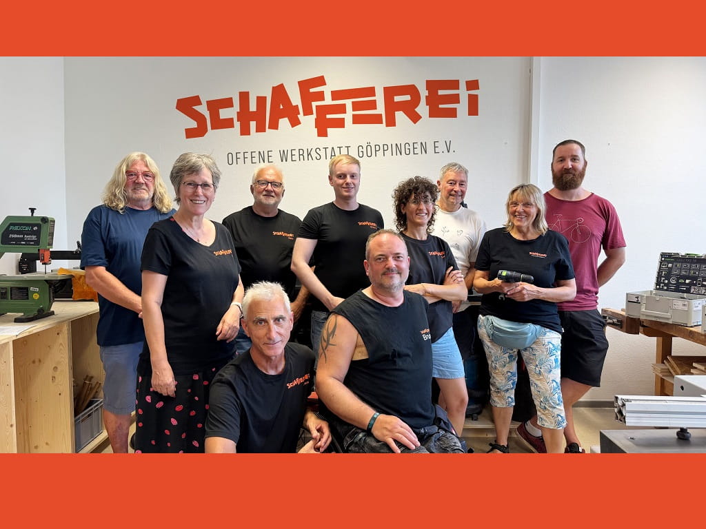Mitglieder der SCHAFFEREI Göppingen stehen gemeinsam vor dem Logo der Offenen Werkstatt auf dem Böhringer Areal.