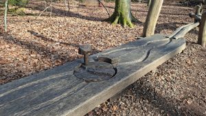 Waldmurmelbahn im Oberholz Göppingen mit geschnitzter Holzbahn und Startmechanismus inmitten eines Laubwaldes, natürliche Spielstation für Kinder entlang des Waldwegs