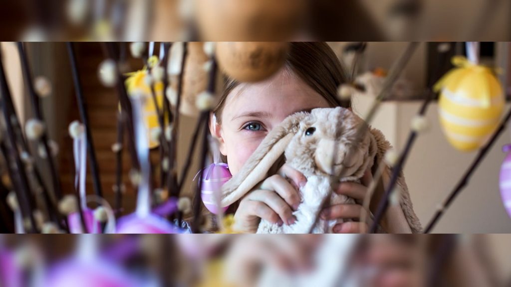 Mädchen mit Stoffhase vor Osterdekoration – Symbol für WirWunder Verdopplungsaktion Ostern 2026