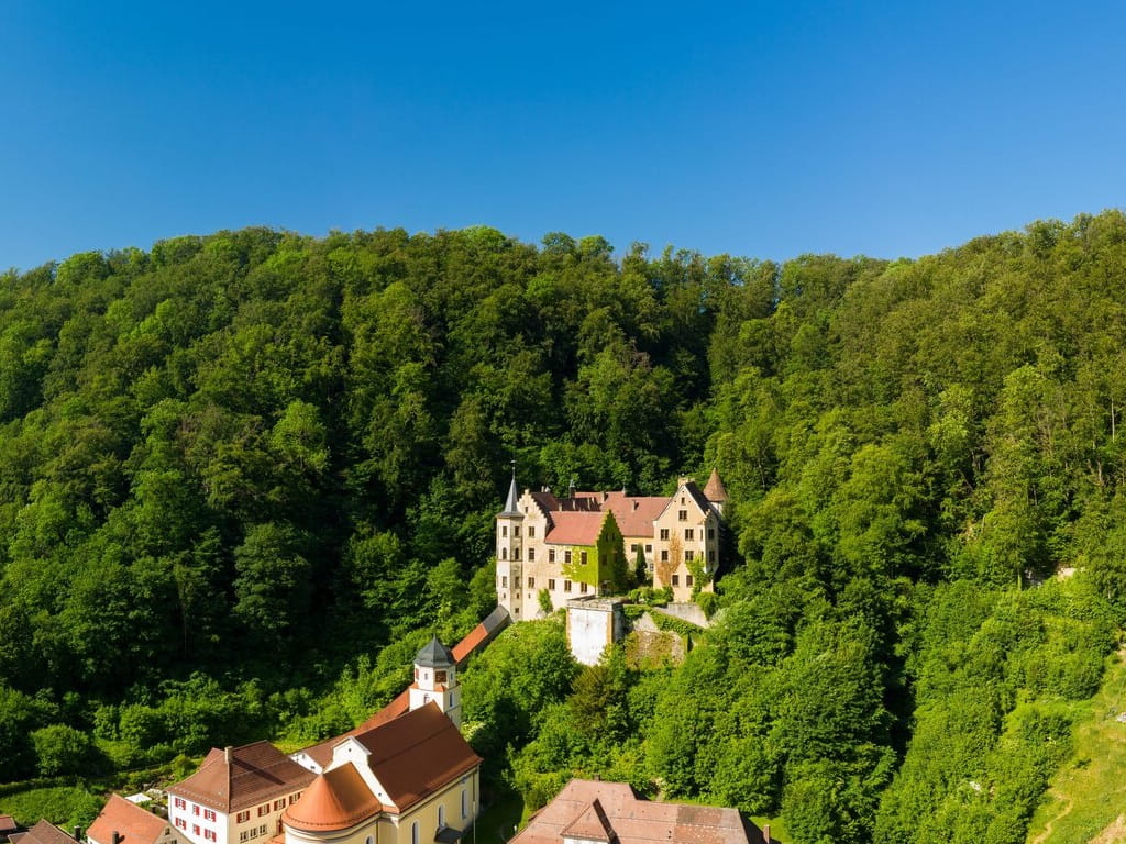 Schloss Weißenstein bei Lauterstein, umgeben von dicht bewaldeten Hängen am Albtrauf
