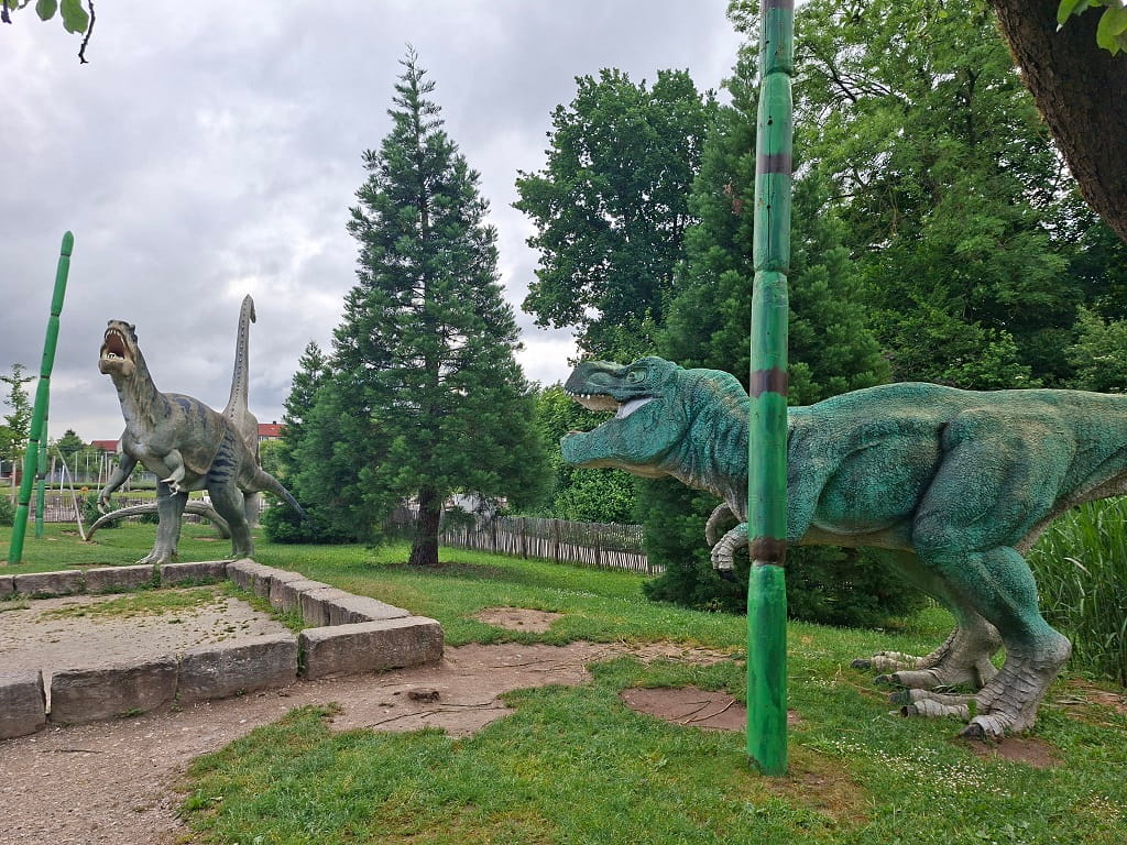 Lebensgroße Dinosaurierfiguren im Dinopark des Himmelsgartens Schwäbisch Gmünd zwischen Bäumen, Grünflächen und Urzeitpflanzen.