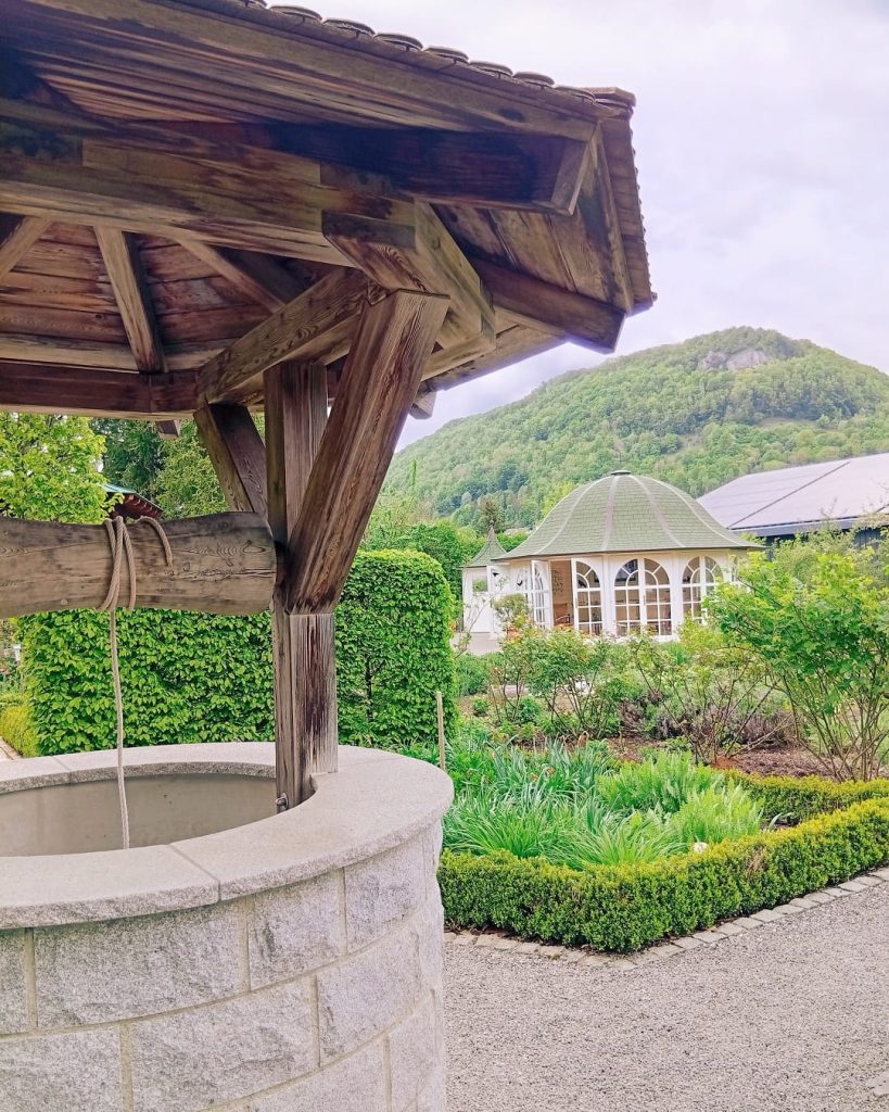 Erlebnis-Kräutergarten Bad Ditzenbach mit Steinbrunnen, Pavillon und grüner Gartenanlage